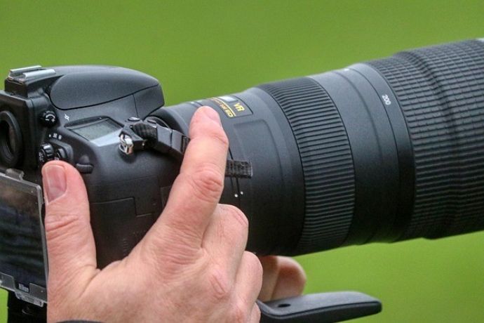 Black and white image of a DSLR camera capturing people in focus, showcasing photography professionalism.